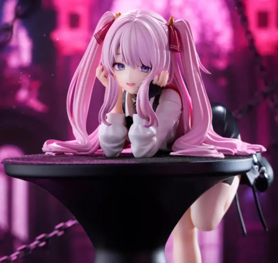 Anime character figurine with pink hair on a black stand against a blurred pink and purple background