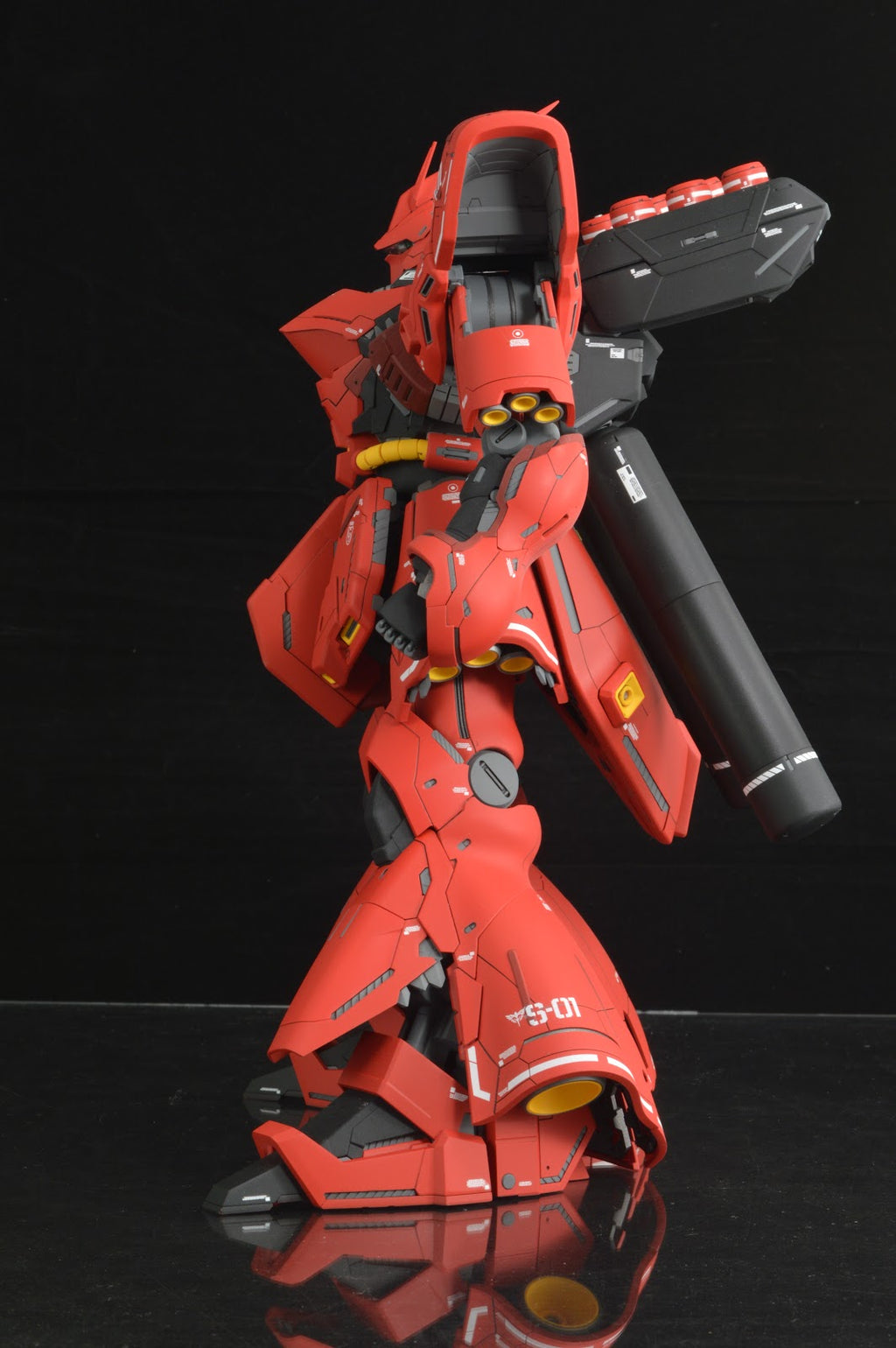 Red robot model on a black reflective surface with a black background