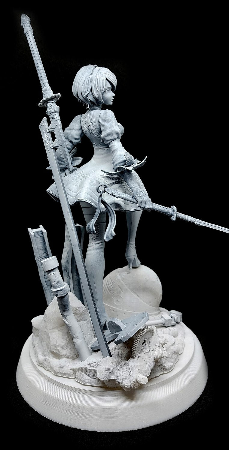 A monochrome unpainted resin figurine of a female warrior character holding swords, posed on a detailed rocky base against a black background.