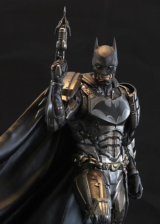 A highly detailed collectible action figure of Batman in armored suit, holding a futuristic gun, set against a dark studio background.