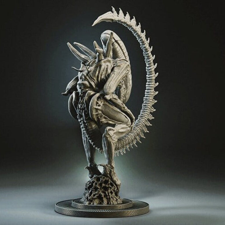 A detailed sci-fi creature statue in a crouched, aggressive pose on a circular base, photographed against a dark studio background.