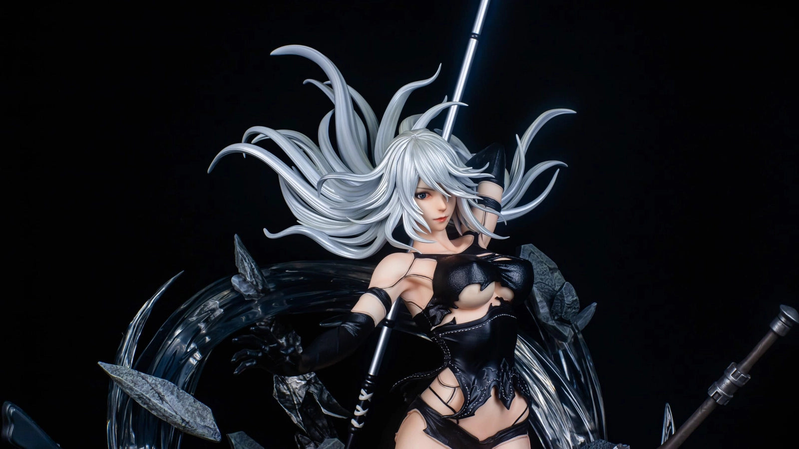 Figure of a character with white hair and black outfit against a dark background