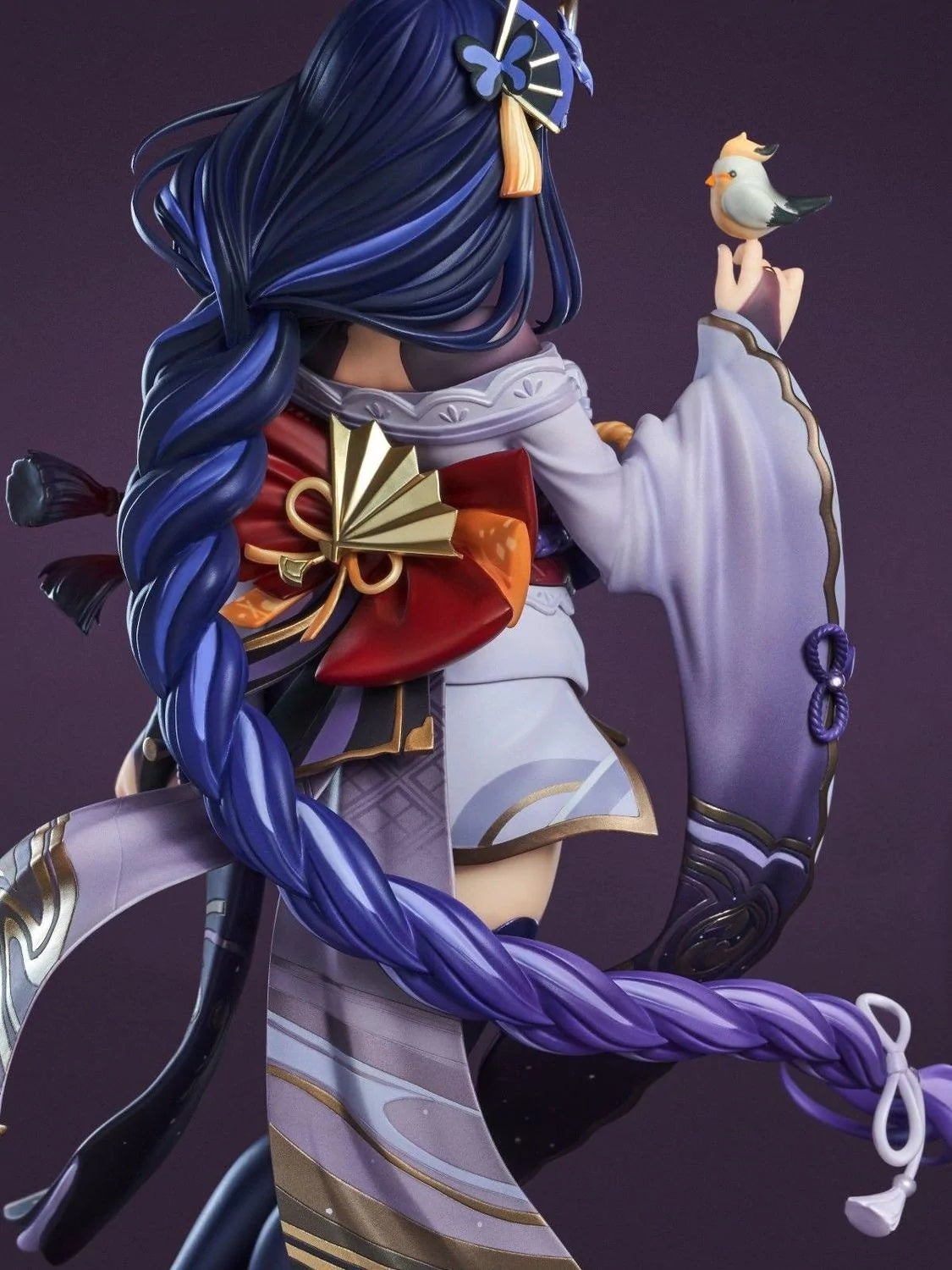 Detailed figurine of an animated character with long blue hair and traditional attire against a dark background