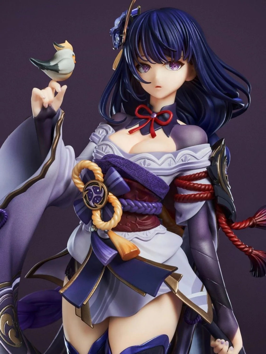 Figurine of a character with purple hair and traditional attire against a dark background