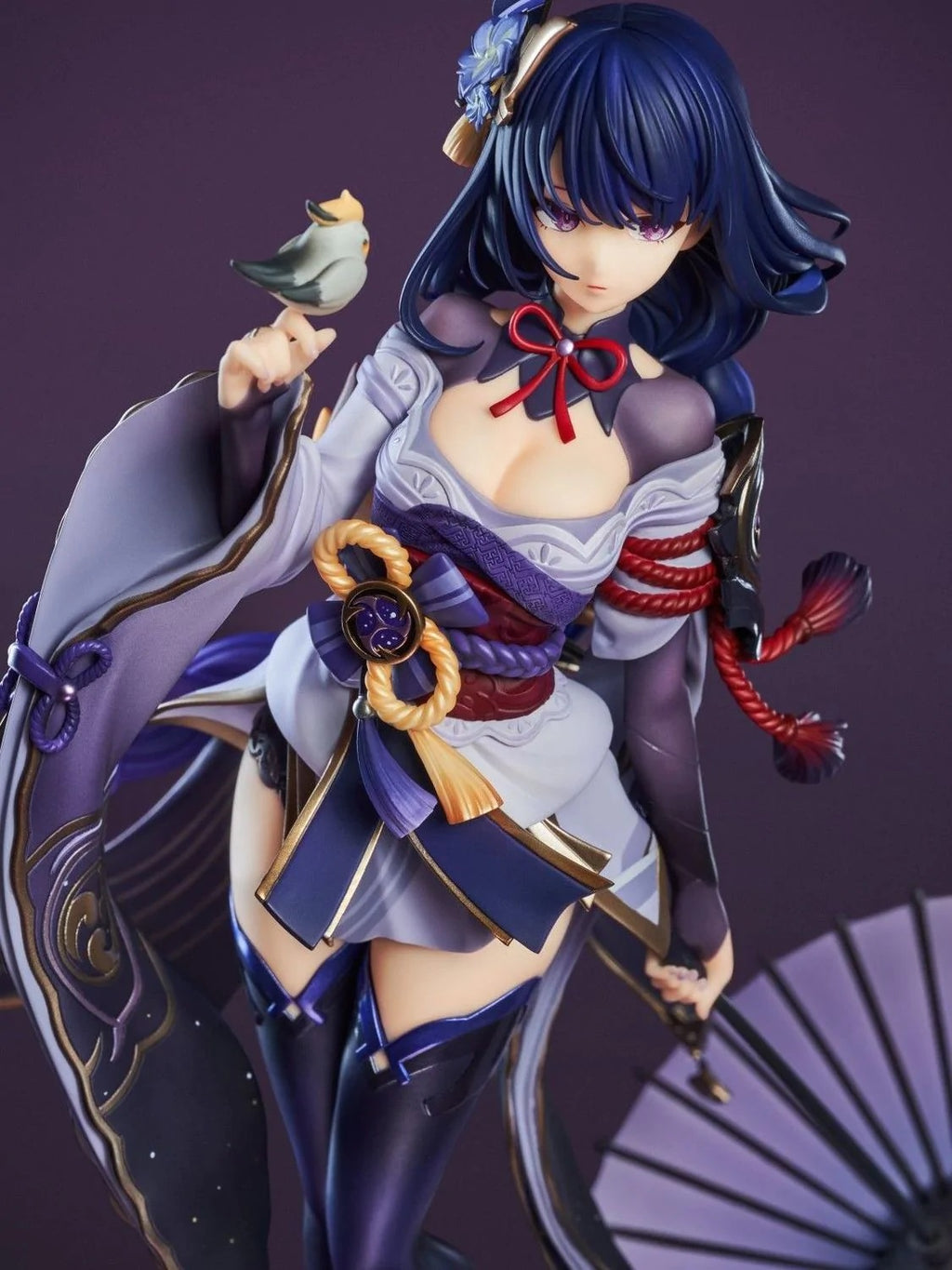 Figurine of a character with blue hair and traditional attire against a dark background