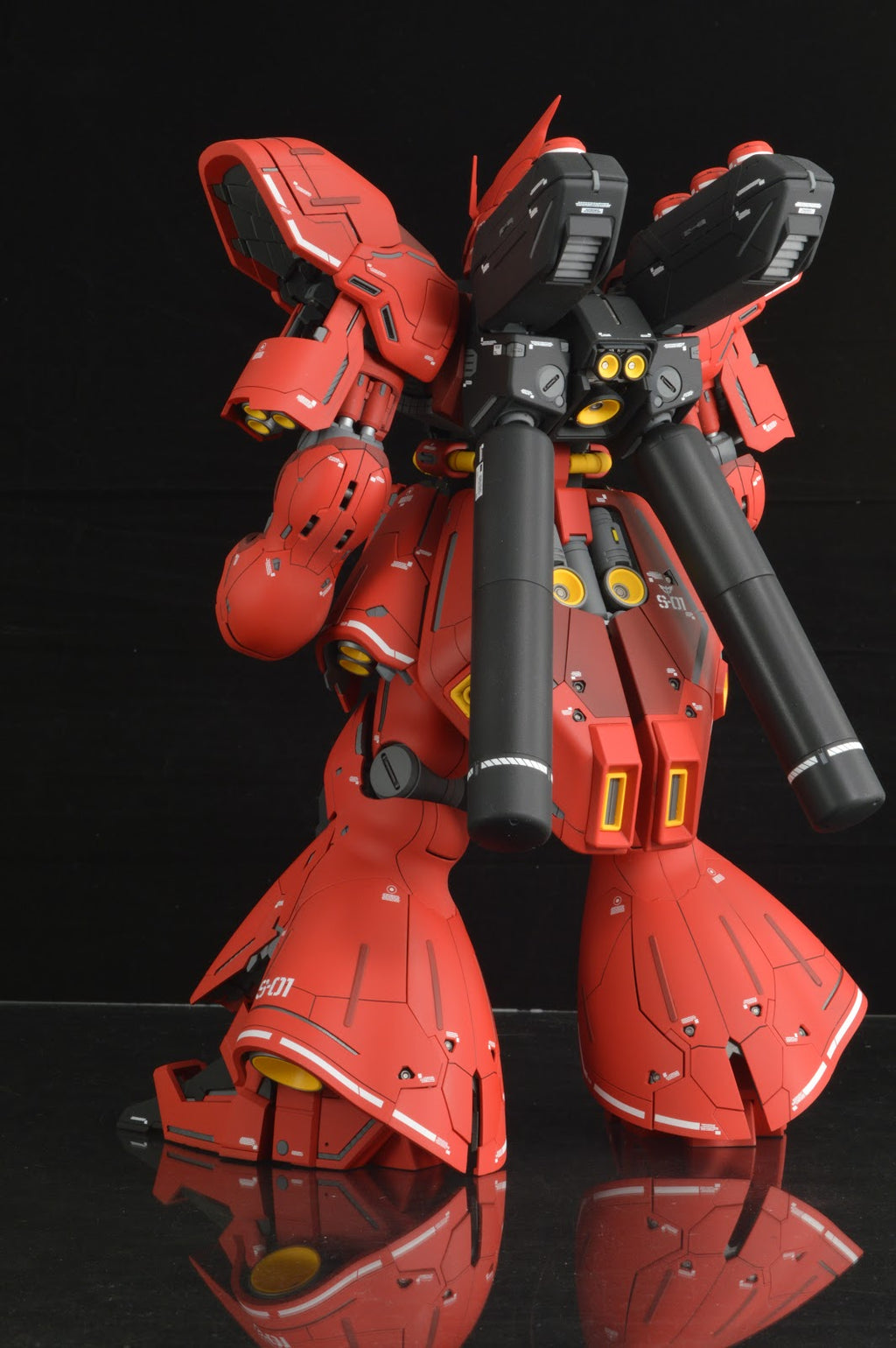 Red robot model with black accents on a reflective surface against a black background