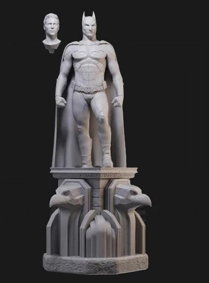 Statue of a superhero on a pedestal with a smaller bust of a man on a black background