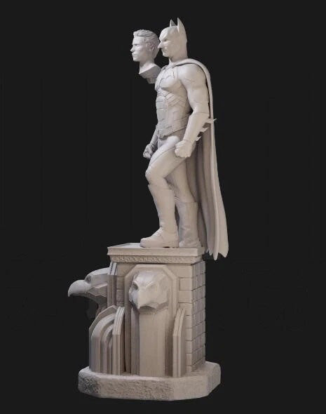 Statue of a superhero and sidekick on a pedestal against a black background