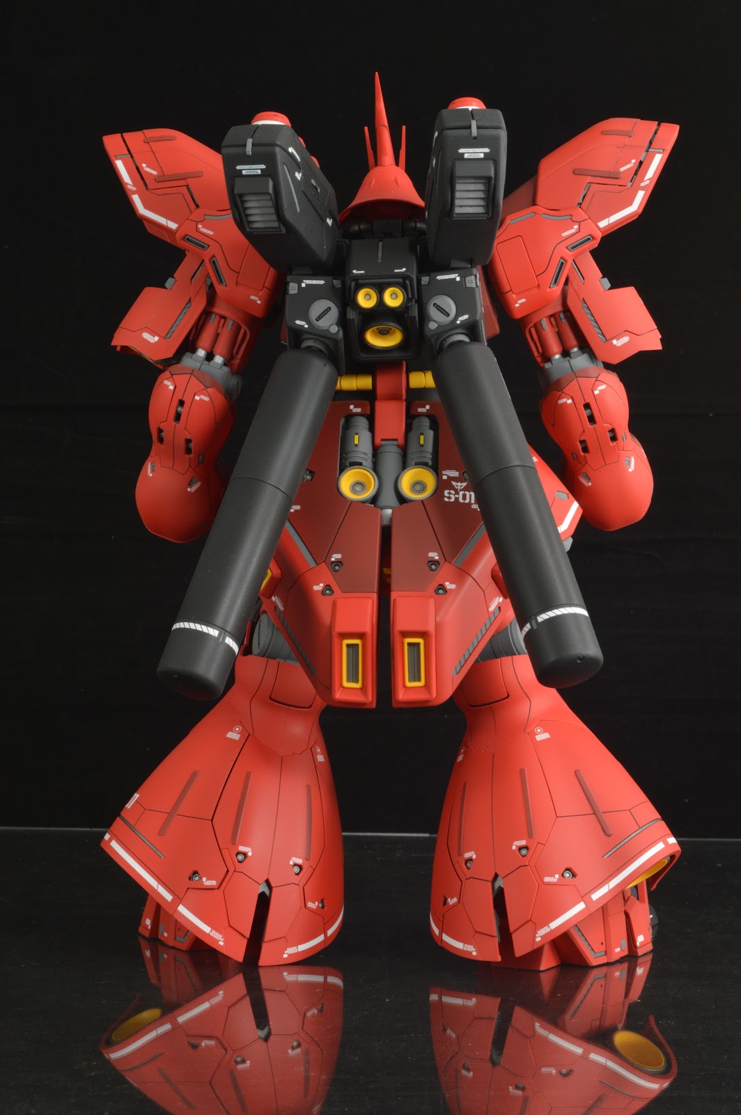 Red and black robot model on a reflective surface with a black background