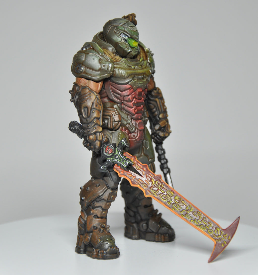 Toy figure of a warrior in detailed armor holding a sword on a gray background