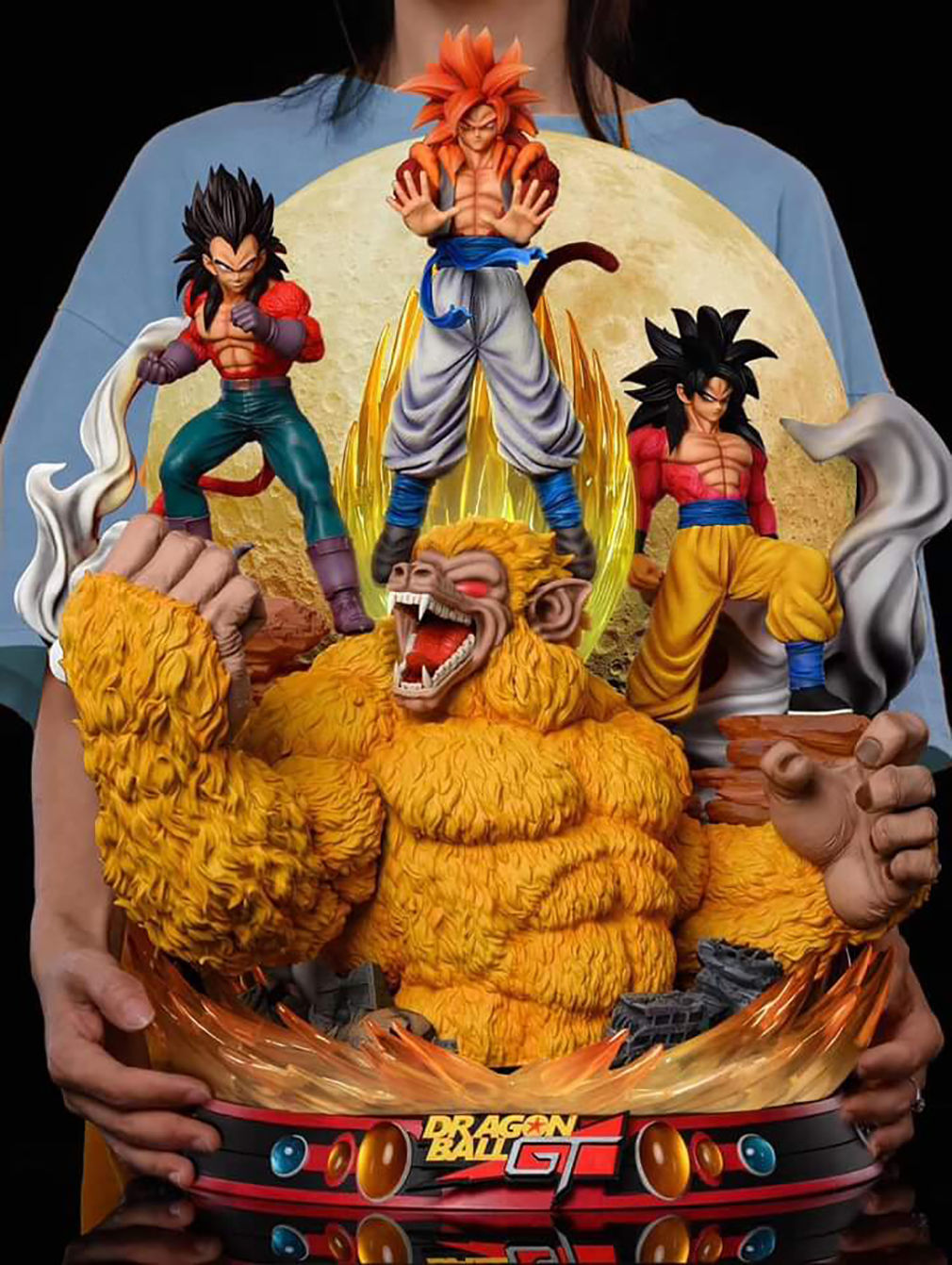 Person holding a Dragon Ball Z figurine with four characters on a black background