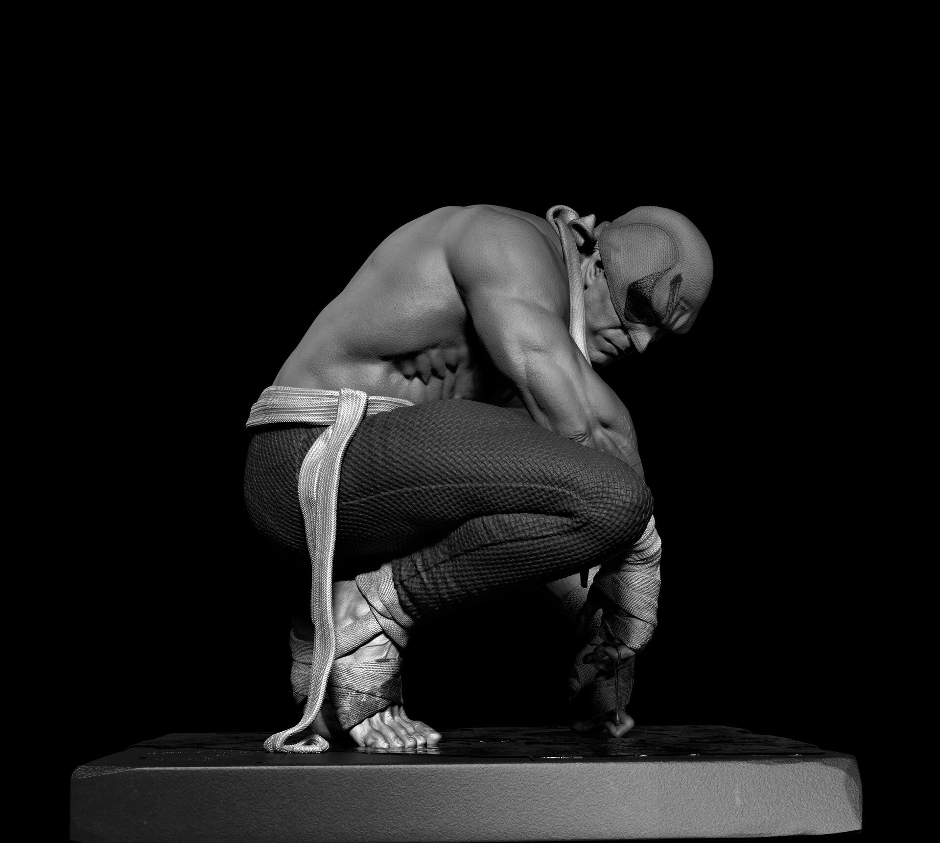 Black and white sculpture of a person in a crouching position on a black background