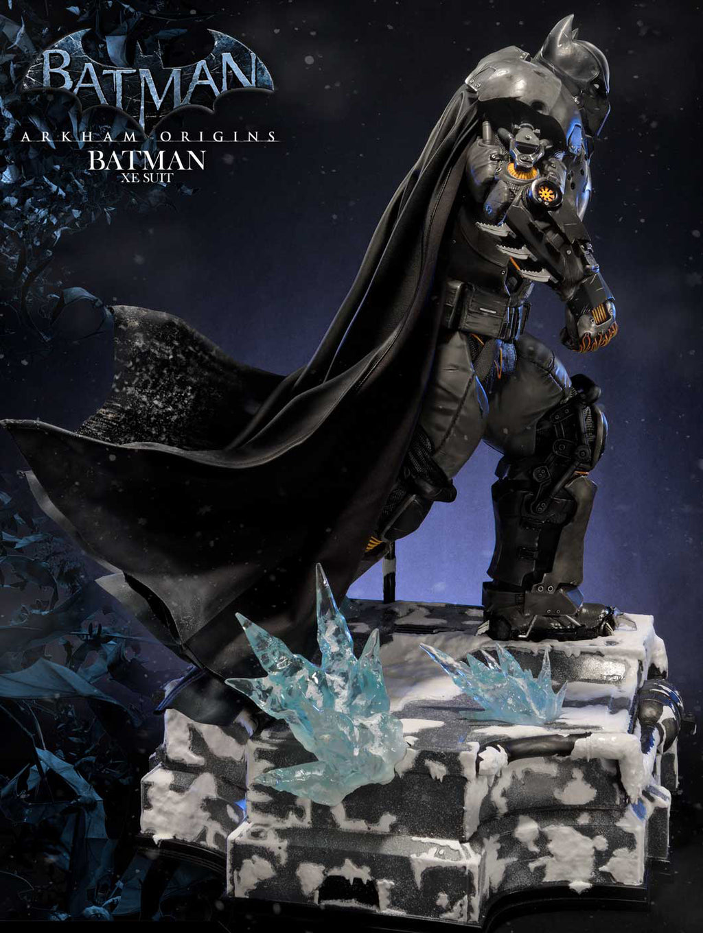 Batman Arkham Origins X-MEN statue in dark armored cowl and cape, posed on a snowy icy base with translucent blue crystal accents against a dark blue background. Batman Arkham Origins X-MEN logo text is visible in the upper left.