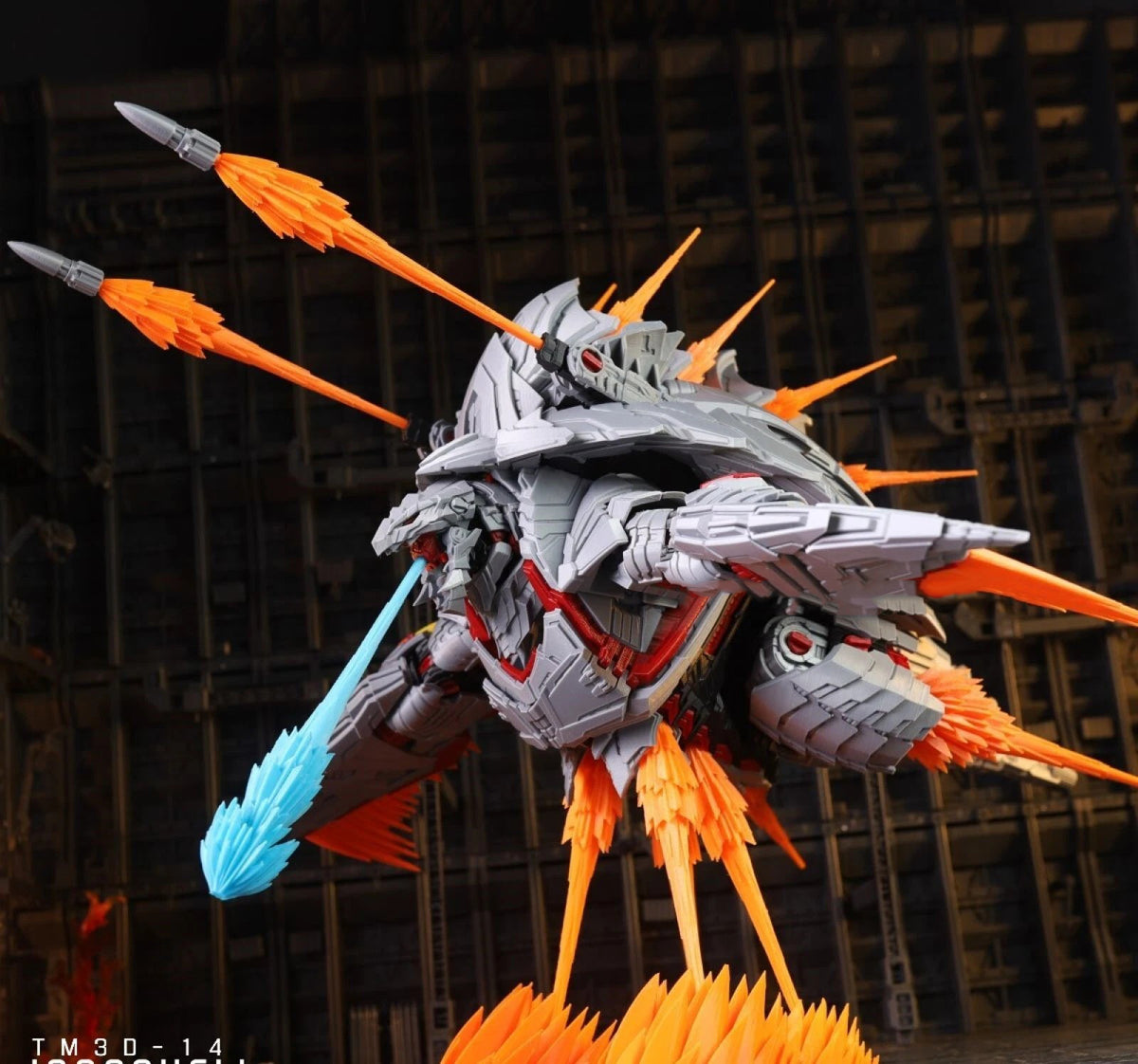 A highly detailed sci-fi mecha model or toy figure in metallic gray armor with bright orange spikes and thrusters, plus a translucent blue blade, posed against a dark industrial background.
