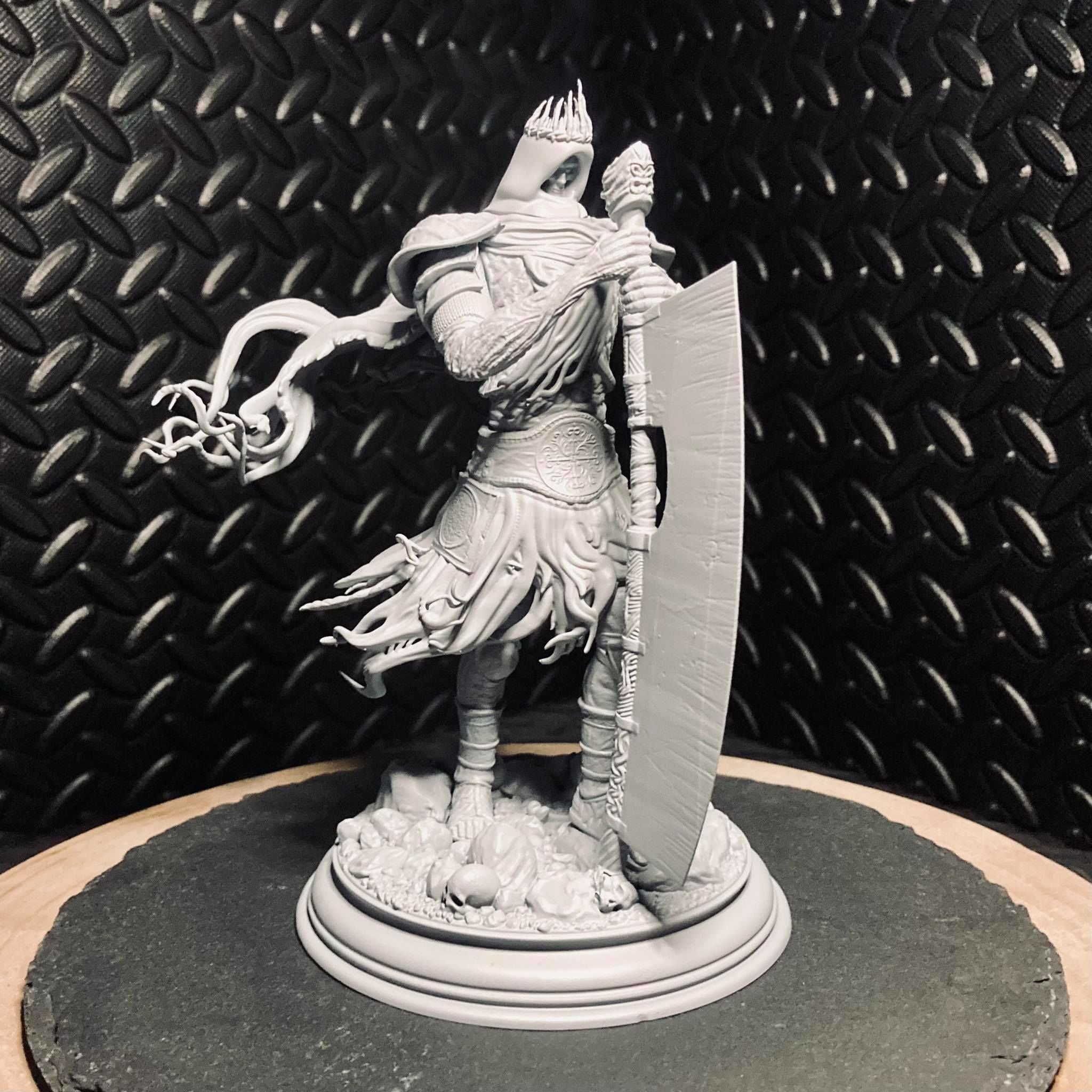 Warrior figurine with armor and shield on a round base against a textured black background